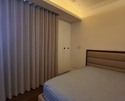 主臥室雙人床與窗簾空間全景，角落一體化嵌入式防盜除濕櫃（防潮箱）完美融入現代室內裝修。