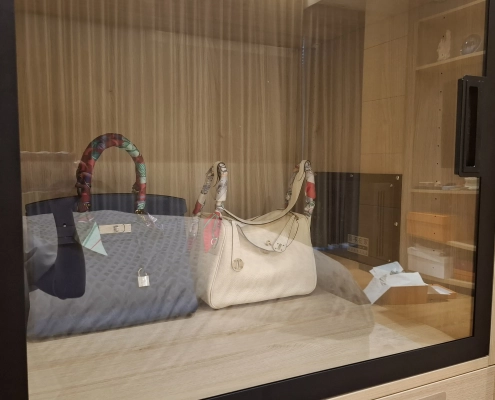 主臥精品除濕防潮櫃近拍，黑框玻璃展示櫃內收納精品包與控制面板