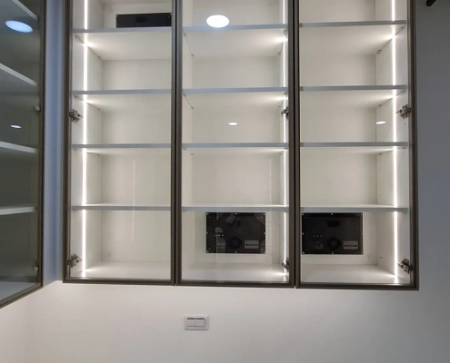 工作室除濕防潮吊櫃內部特寫，鋁框玻璃門內建垂直照明與自主研發除濕模組，手辦模型分區防潮收納