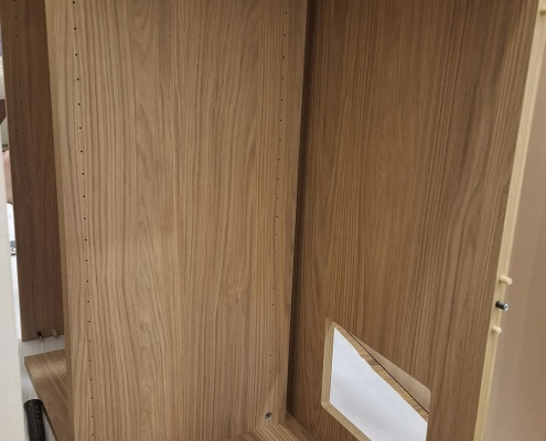 除濕防潮系統展示櫃現場組裝照：量身客製的木紋櫃體骨架落位，側板精準開孔預留除濕模組與排風迴路，展現現場嵌合施工細節。